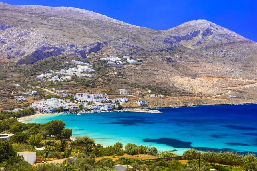 A Greece beach with blue water and a mountain in the background on Amorgos Island.