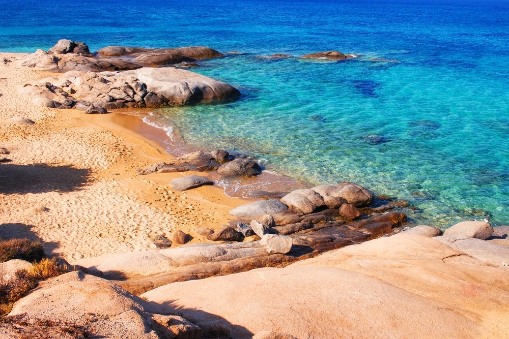A sandy beach in Naxos with blue water and rock - Agia Anna beach on Naxos island, Greece