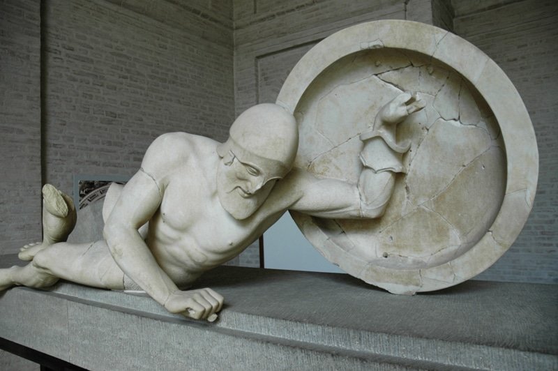 A famous Greek statue of a man laying on a stone.