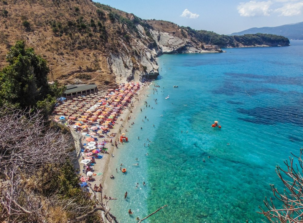 One of the best beaches in Albania, filled with umbrellas and people enjoying the sun.