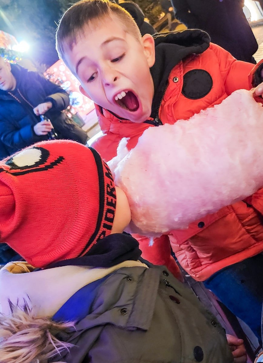 Advent in Zagreb brings a magical atmosphere as a group of children joyfully indulge in cotton candy at night.