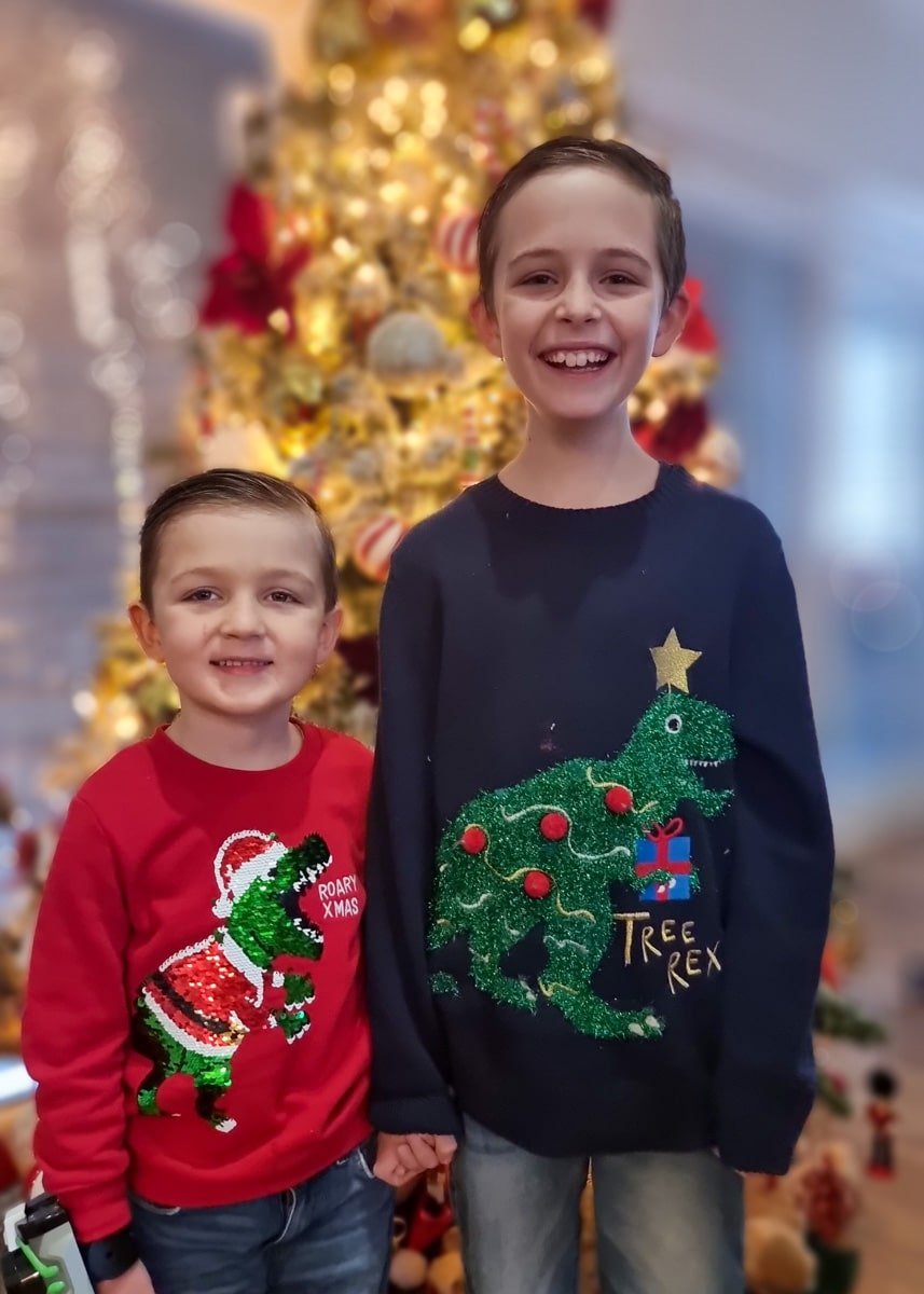Vladimir & Roko wearing ugly Christmas sweaters in front of a Christmas tree during Christmas In Zagreb