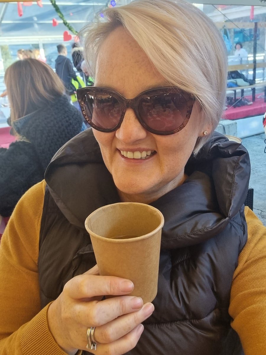 SJ in sunglasses enjoying Advent in Zagreb, holding a cup of coffee.