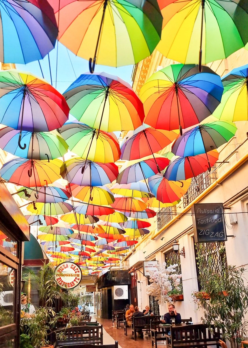 Colorful umbrellas hanging from the ceiling of a restaurant at Pasajul Victoriei - Umbrella Street