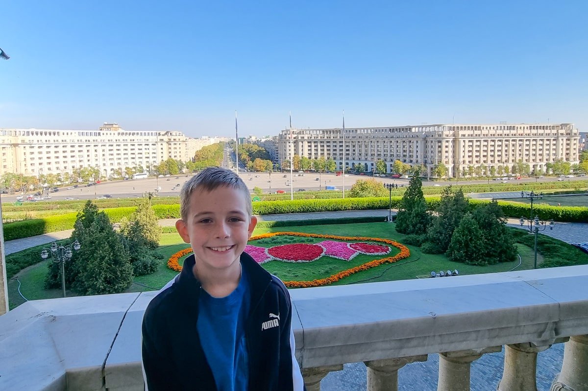 Vladimir standing on a balcony overlooking a city at the Palace of Parliament in Bucharest.