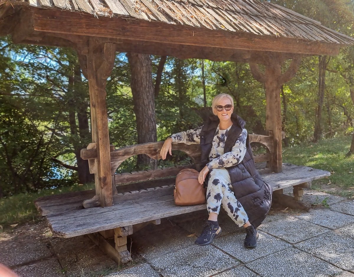 SJ sitting on a wooden bench in a park in Romania