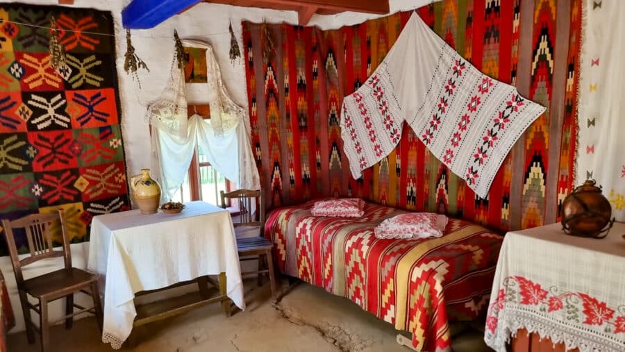 A room with a bed and a bedclothes A room with a bed and a spinning wheel in the Dimitrie Gusti National Village Museum