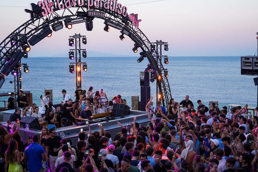 A crowd of people at a tranquil concert on the beach in Mykonos beach clubs.