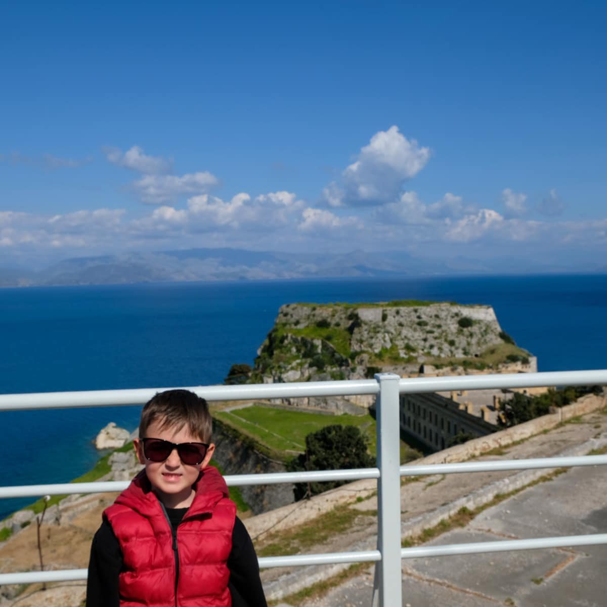 Roko wearing a red jacket exploring Greek landmarks in Greece, particularly the Corfu Old Venetian Fortress