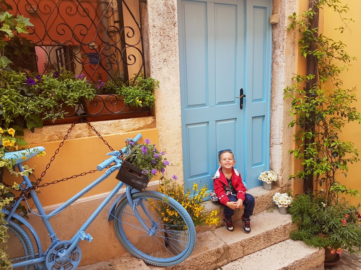 Vladimir sitting on the steps next to a blue bicycle in Rovinj, Croatia