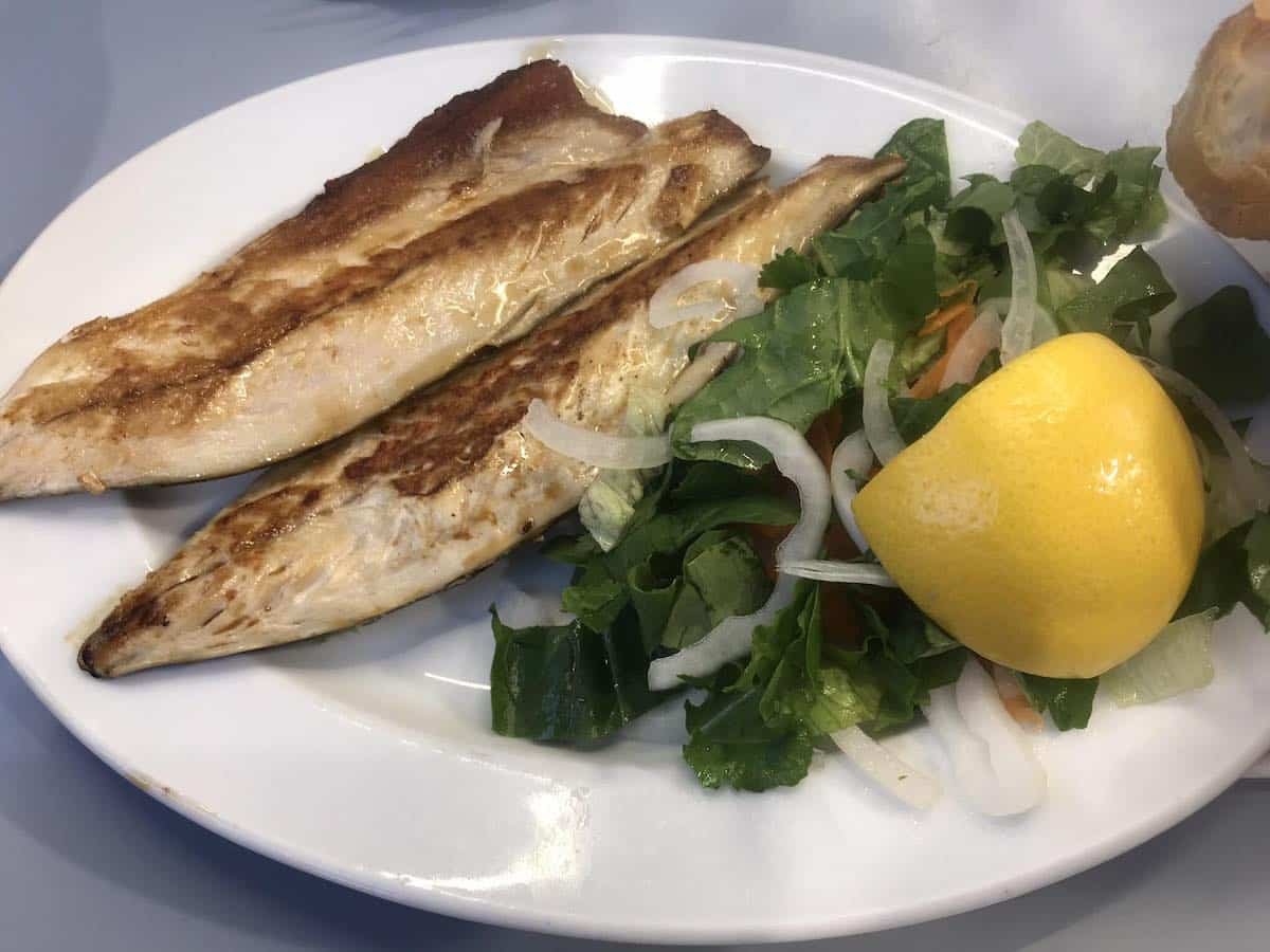 A plate of fish and salad on a table.