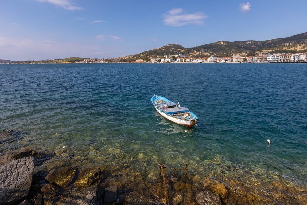 A boat sailing in the turquoise waters, surrounded by the stunning landscapes of Izmir's best beaches.