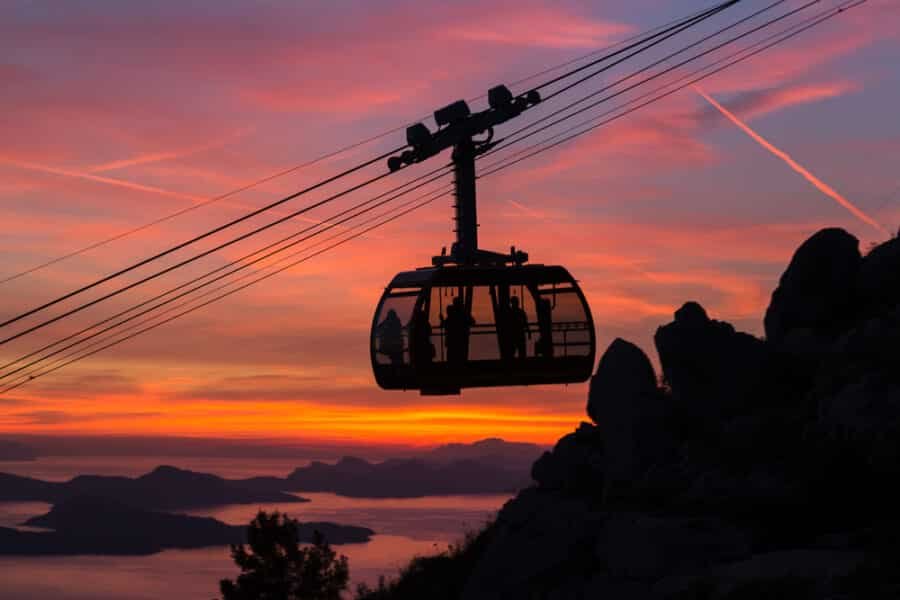 Experience the Dubrovnik Cable Car with passengers onboard, offering stunning views of the city below - at sunset