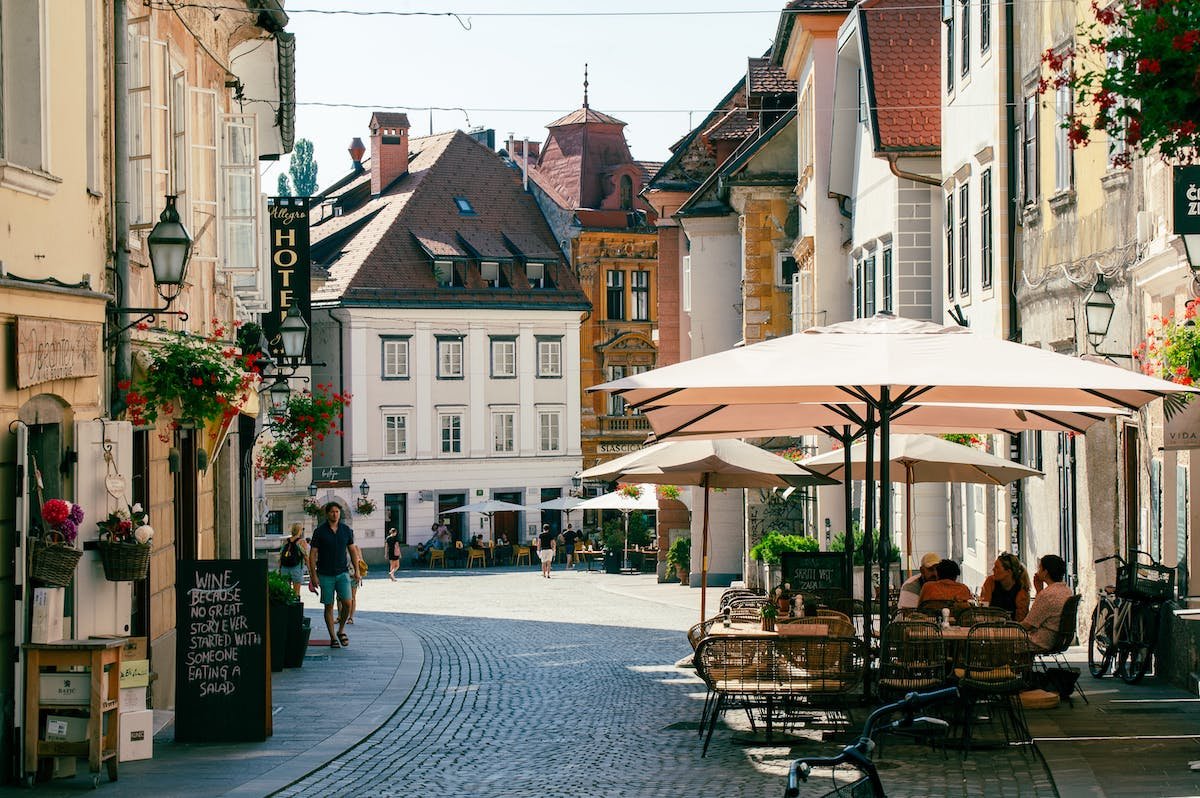 One of the charming things to do in Ljubljana is walking along a cobblestone street lined with tables and umbrellas, enjoying a peaceful atmosphere.