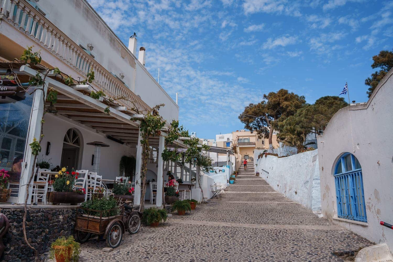 A cobbled street in a white building with blue shutters, part of a 3 Day Santorini Itinerary.