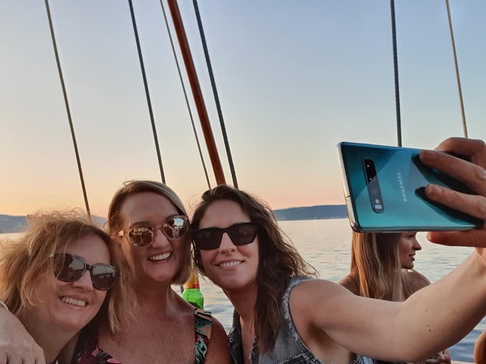 Three women taking a selfie on a sailboat.