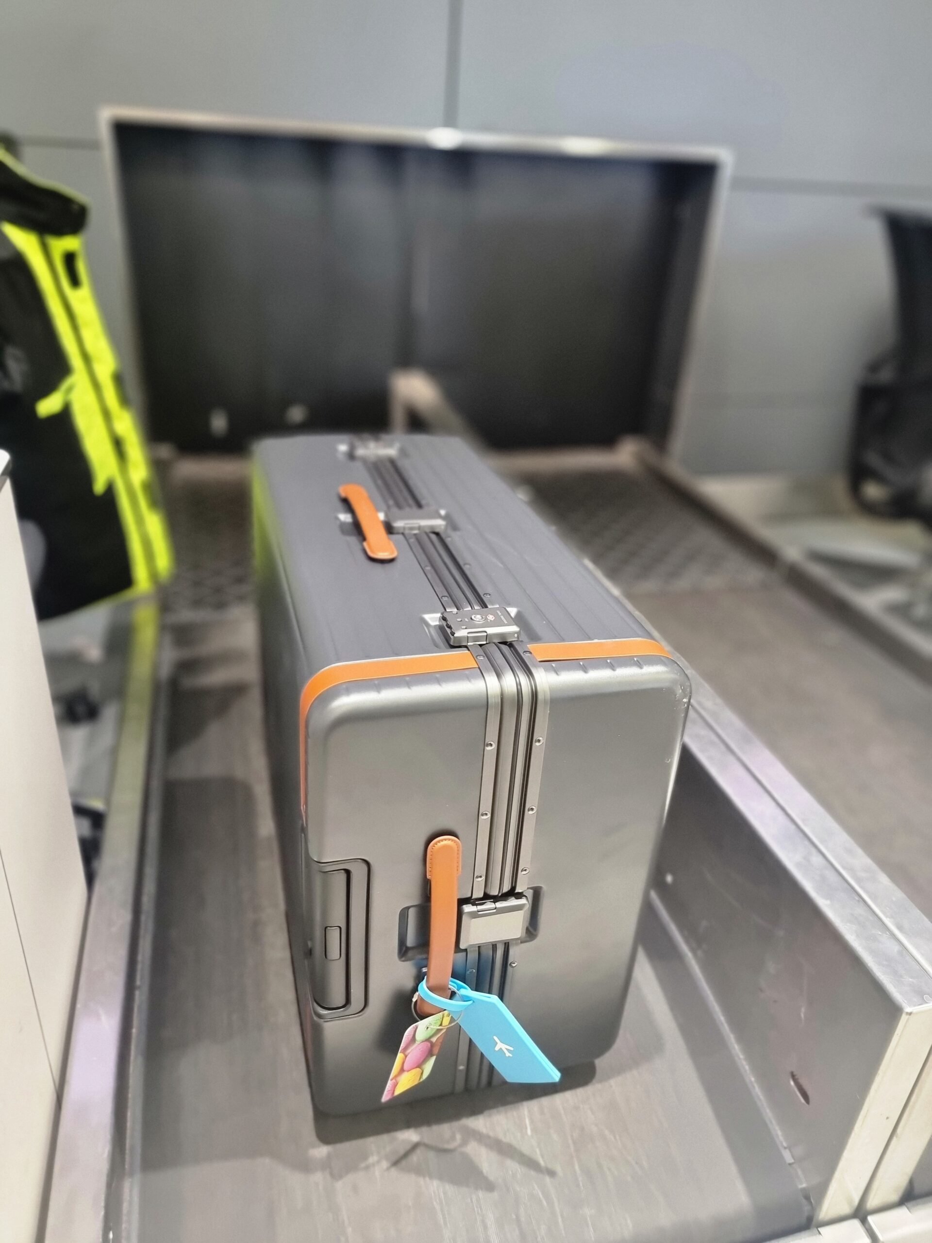 A Carl Friedrik - The Check-in zipperless suitcase sitting on a conveyor belt at an airport.