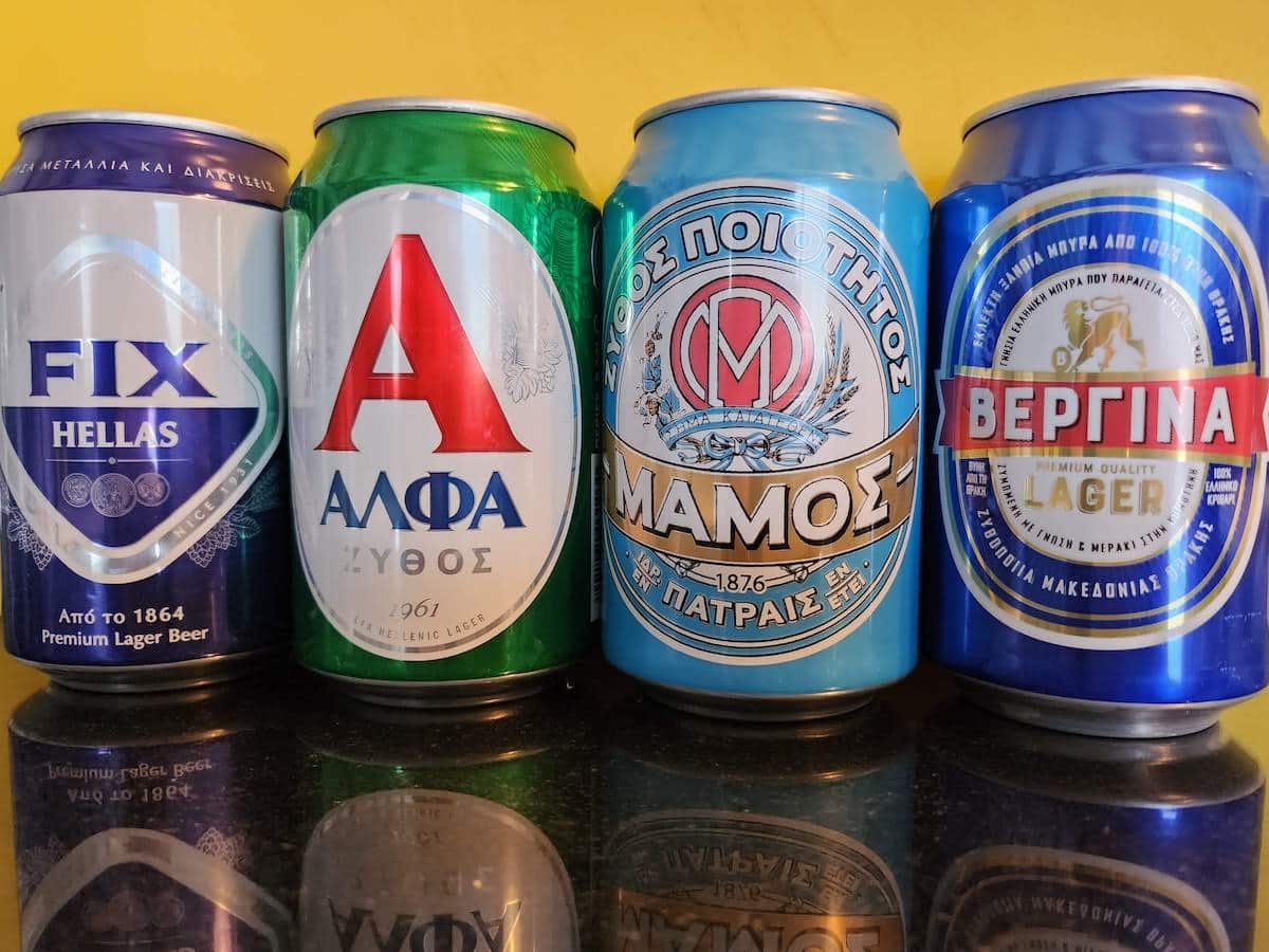Four cans of Greek beer are lined up on a table.