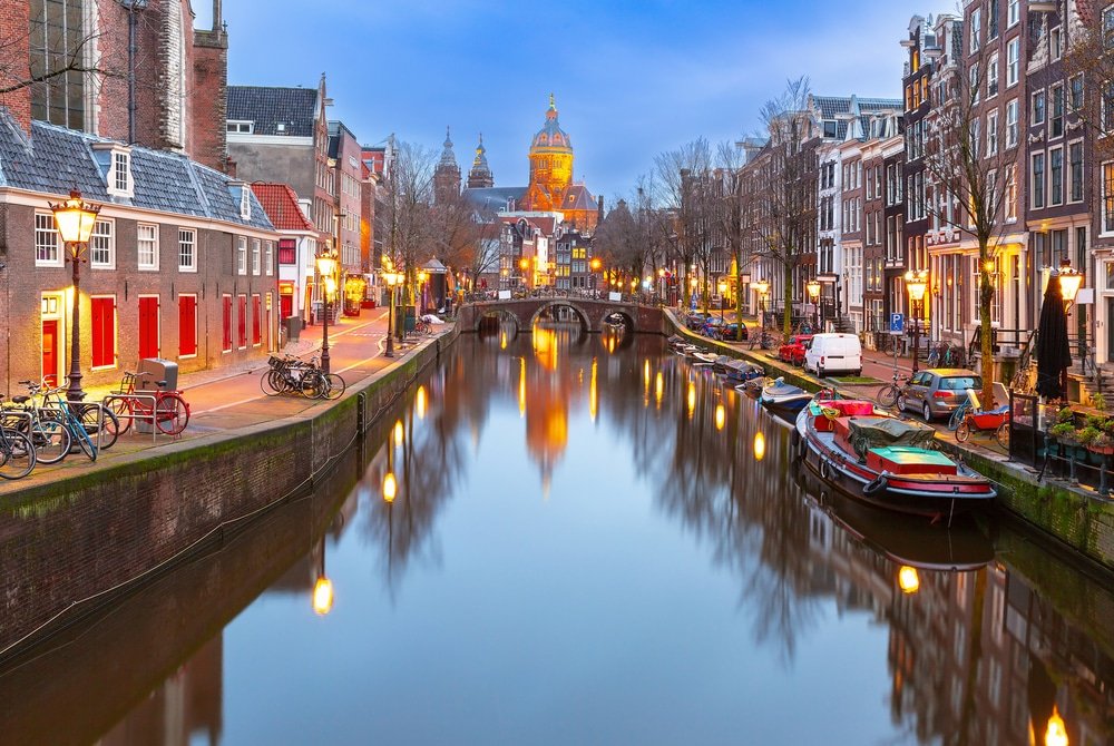 An Amsterdam adventure along a canal lined with buildings at dusk.