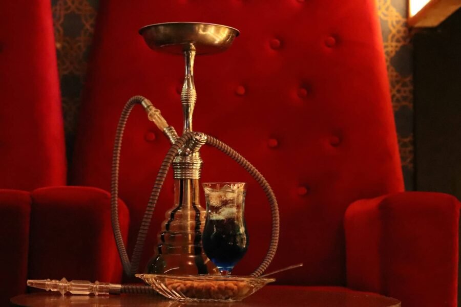 In Izmir's vibrant nightlife scene, a hookah is elegantly placed on a table beside a striking red chair, setting the stage for an unforgettable evening of Things To Do.