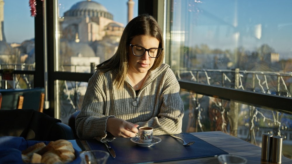 A woman enjoying the best Turkish coffee in Istanbul at a table.