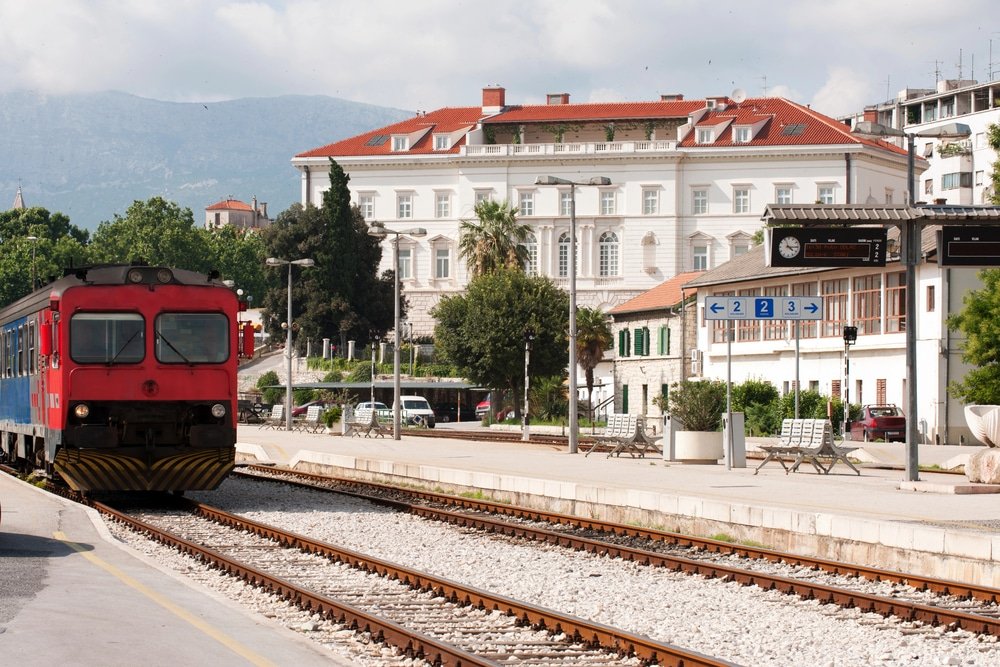 A red train traveling on the tracks from Split to Zagreb