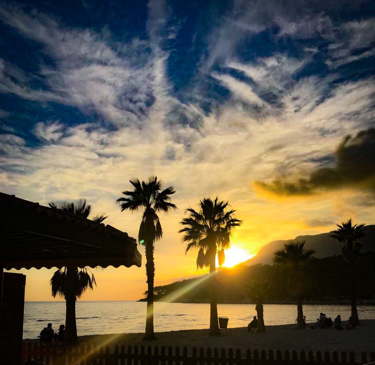 A sunset over Akyaka with palm trees.