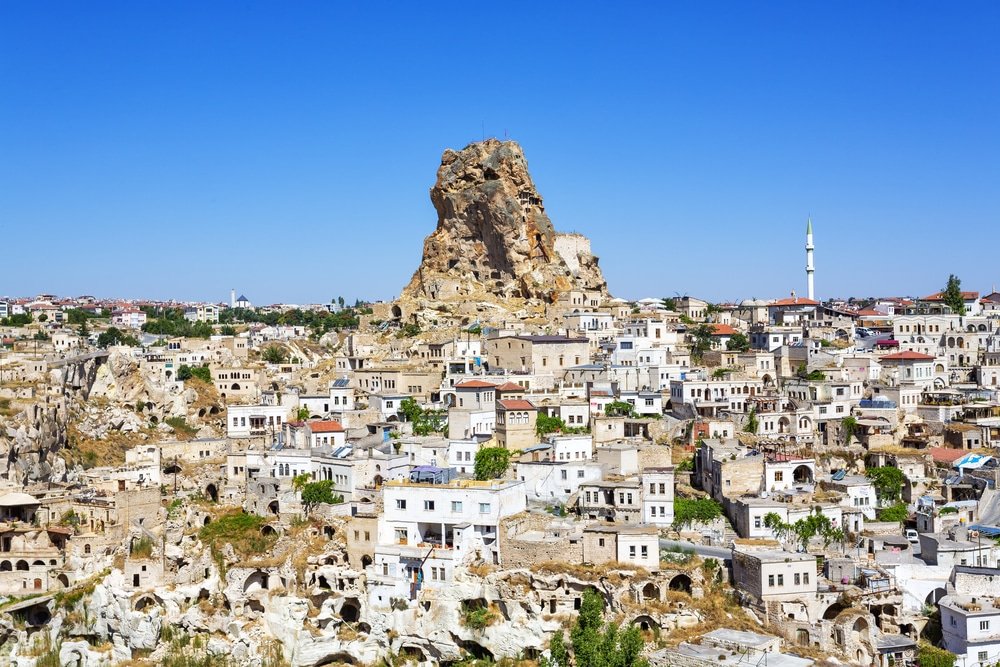 A panoramic view of the town of Ortahisar in Cappadocia, Turkey, renowned for its rock castle, featuring traditional stone houses, caves, and restaurants.