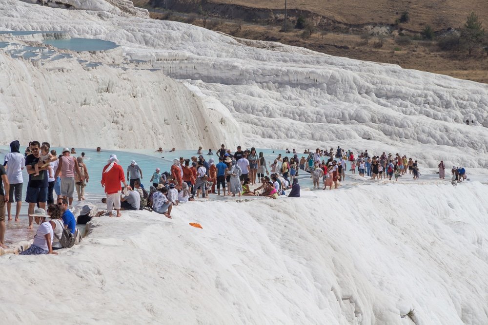 A group of people standing on the edge of the hot springs in Pamukkale summer in Turkey.