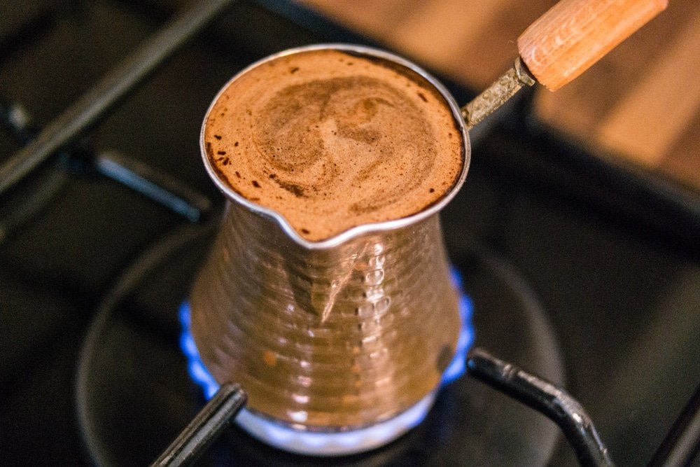 Turkish coffee cooking on a copper pot on a stove.