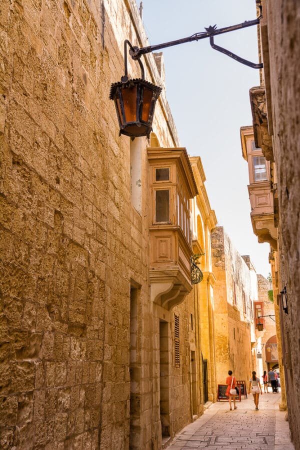 A stone wall with a lamp hanging from it in Mdina, Malta.