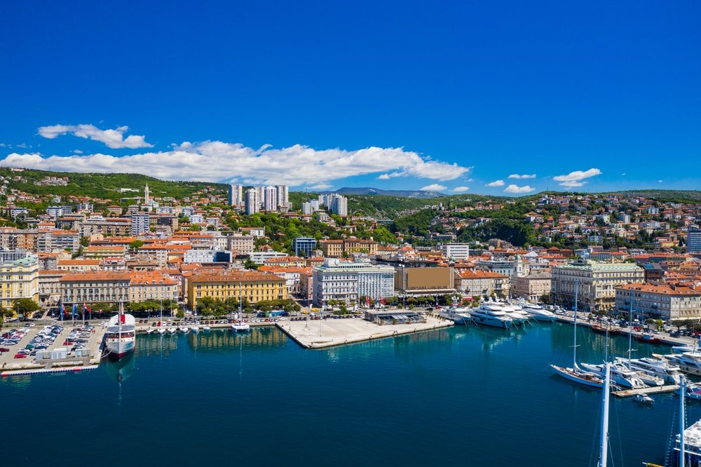 Aerial view of a bustling coastal city in Croatia with marina and clear blue skies.