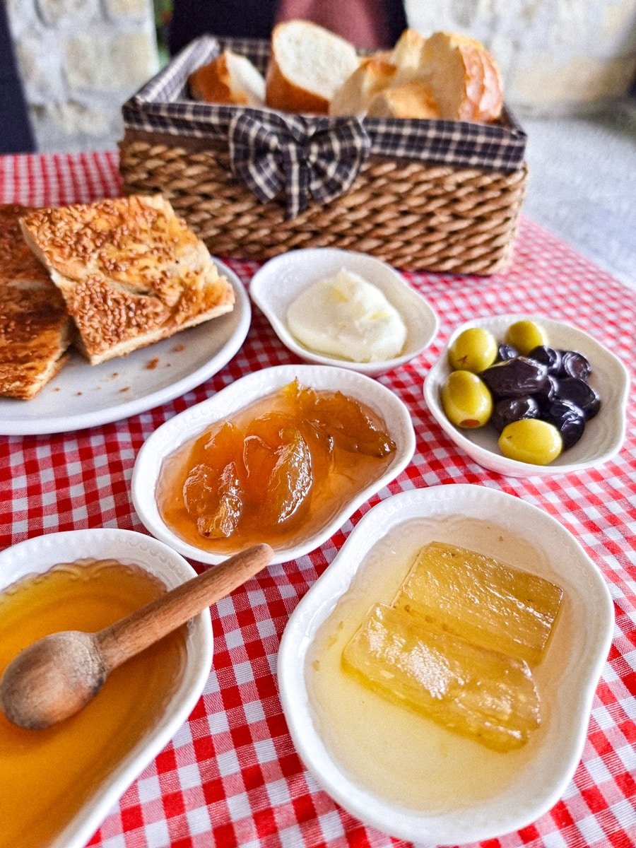 A breakfast spread with toast, jam, butter, and olives served on a red and white checkered tablecloth in Avanos, Cappadoccia, Turkiye.