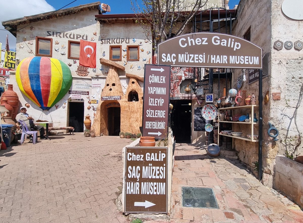 Exterior of Chez Galip Hair Museum in Avanos, Cappadocia, Turkey, featuring colorful ceramic displays and a hot air balloon decoration under a clear blue sky.