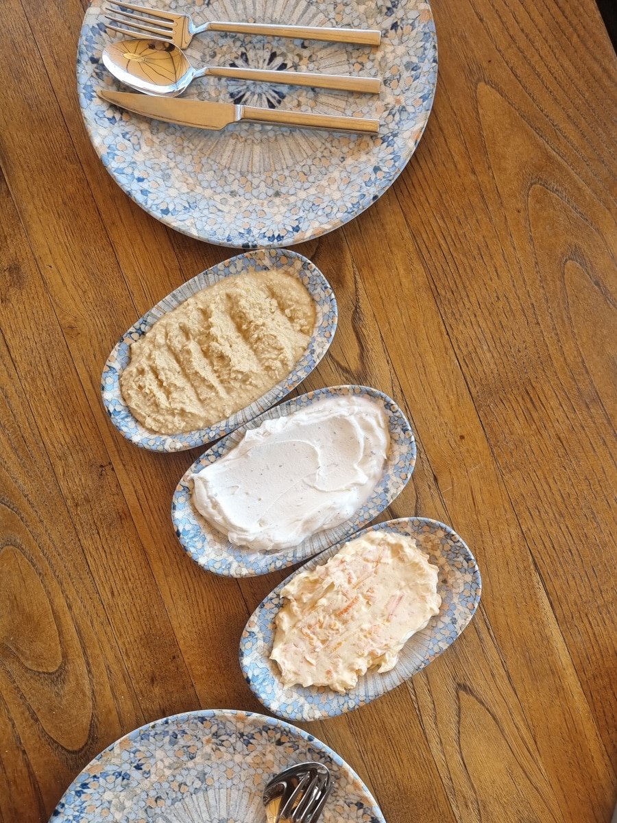 Four oval plates with various spreads, arranged on a wooden table, beside neatly placed utensils, showcasing things to do in Avanos Cappadocia, Turkiye.