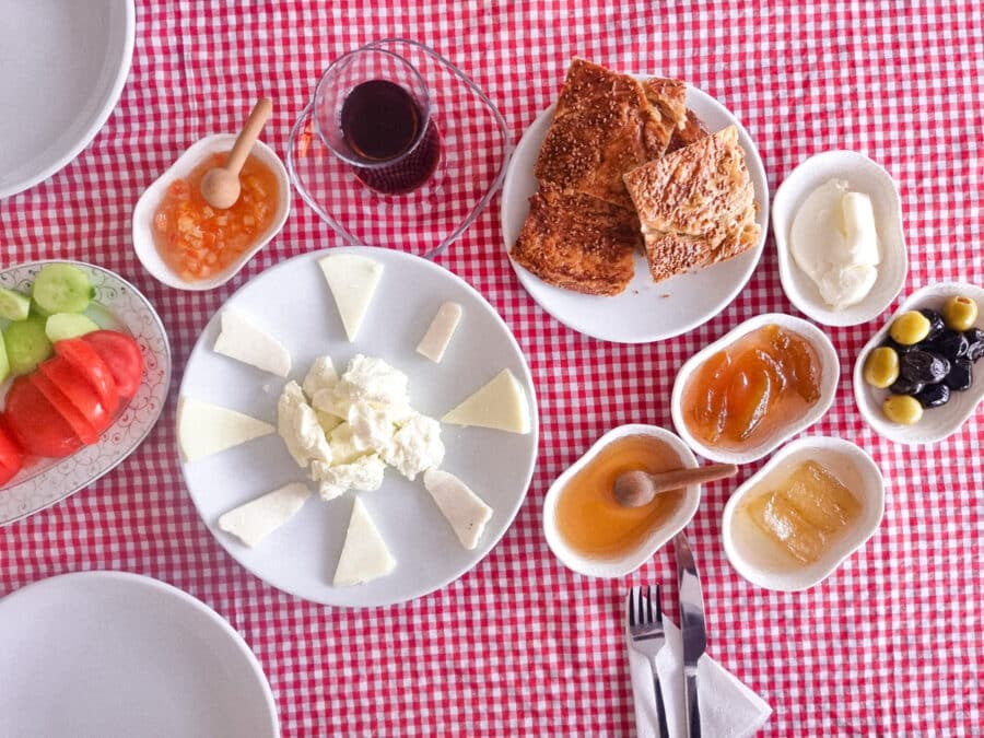 A traditional Turkish breakfast spread on a red and white checkered tablecloth, featuring cheese, bread, jams, honey, and fresh vegetables in Avanos Cappadocia, Turkiye.