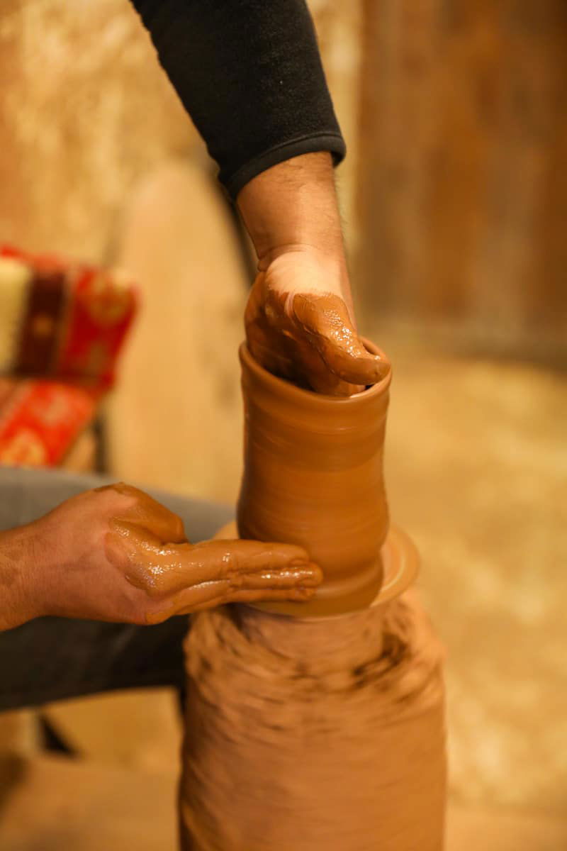Person shaping a clay pot on a pottery wheel, hands covered in wet clay, one of the traditional things to do in Avanos, Cappadocia, Turkiye.