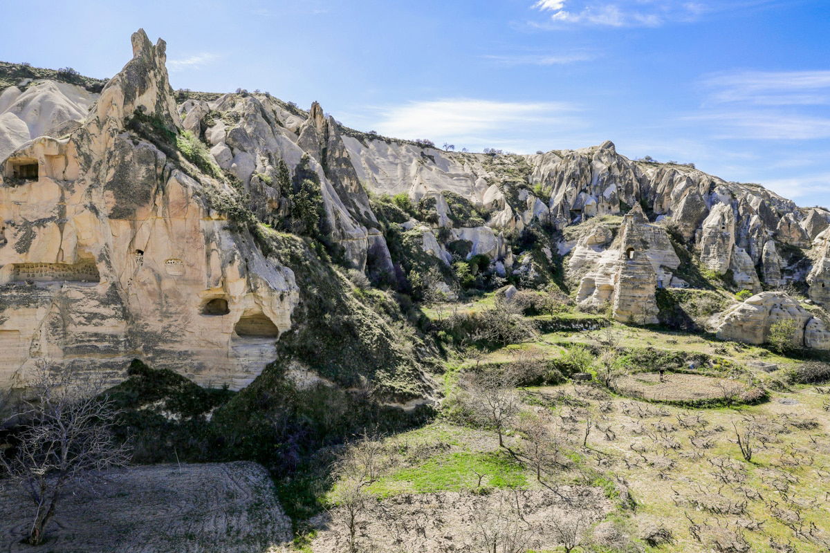 Rocky landscape near Goreme Open Air Museum with weathered stone formations and sparse vegetation under a clear sky in Cappadocia, Turkey.