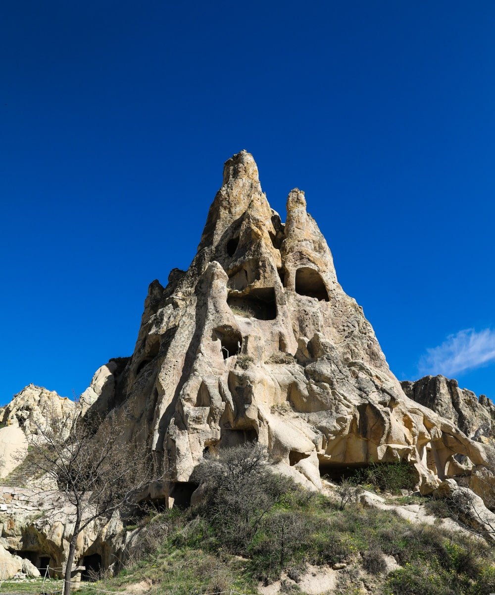 Rock formations with cave dwellings in the Goreme Open Air Museum under a clear blue sky.