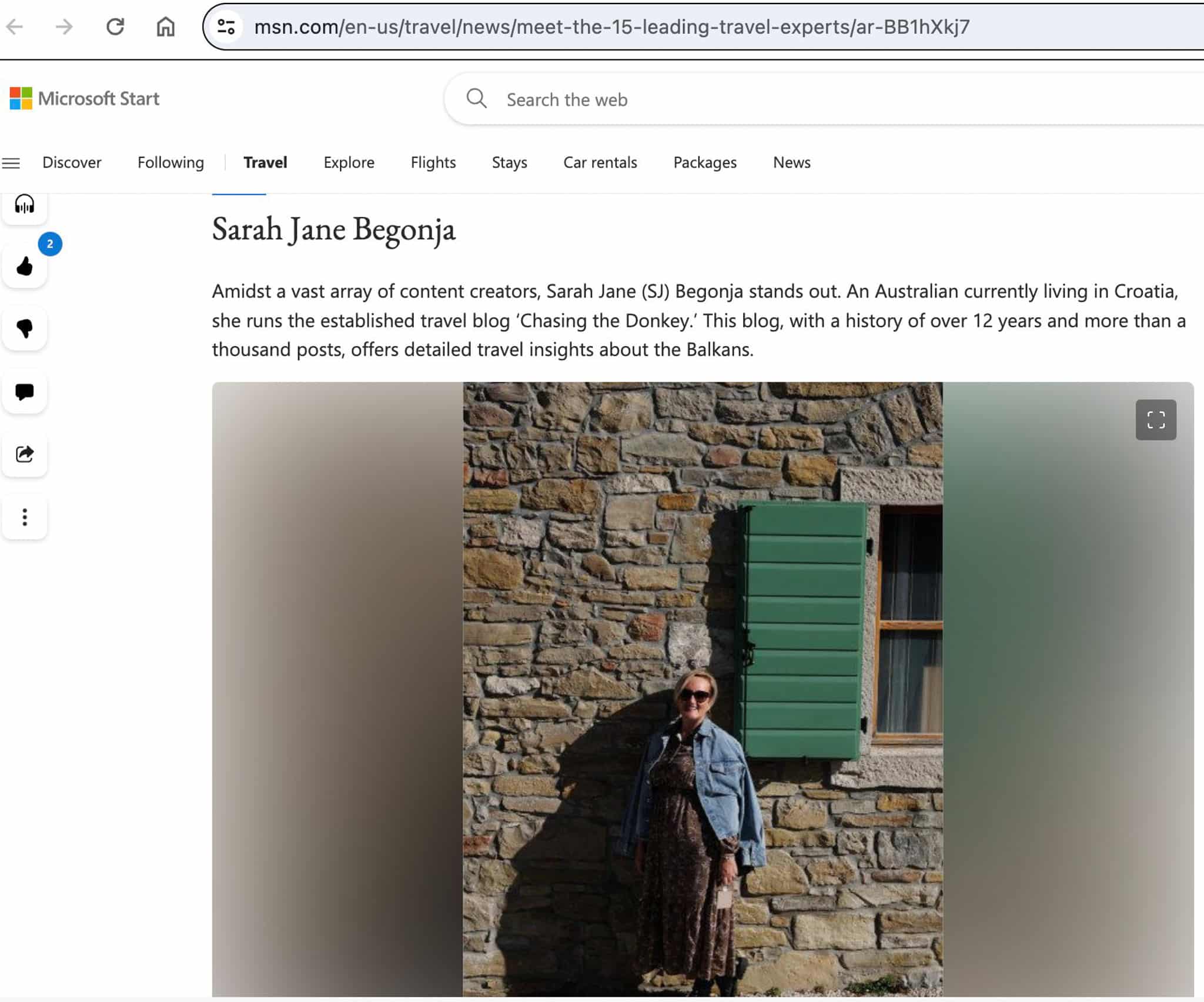 Woman in sunglasses and a blue scarf standing in front of a stone wall with a green window shutter, featured on her travel blog.