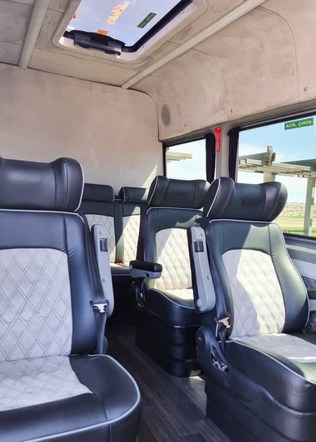 Interior of a Turkey transport shuttle bus showing rows of quilted leather seats with headrests, aisle, and ceiling details visible.