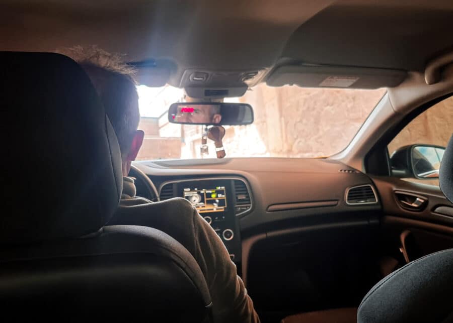 Interior view of a car with a driver from behind, featuring the dashboard, steering wheel, and the rear-view mirror in Turkey.