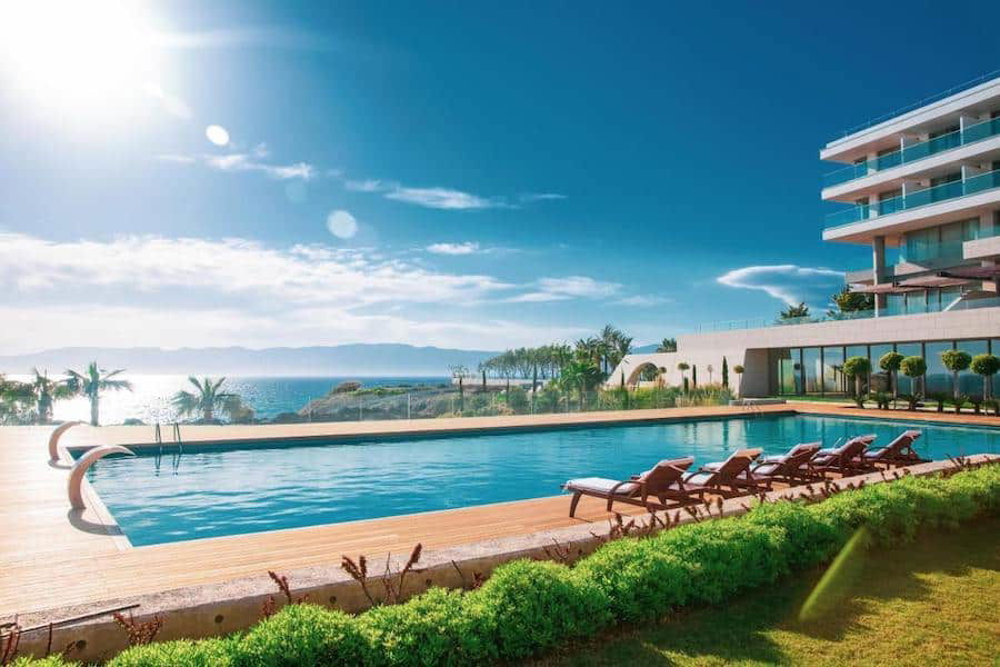 Luxury hotel infinity pool overlooking the sea with sun loungers on a sunny day in Çeşme.