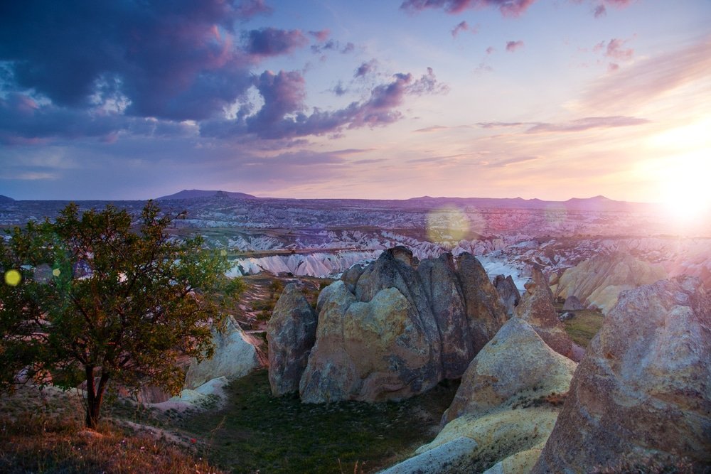 Best sunset spots in Cappadocia feature a rugged landscape with large, soft-colored rocks and sparse greenery.