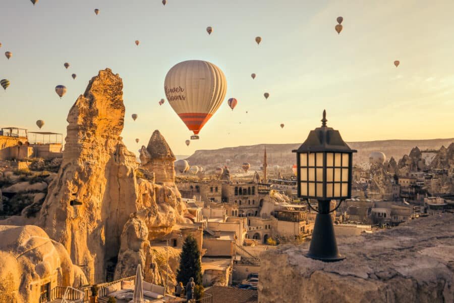 Hot air balloons floating over Cappadocia's rocky landscape at sunrise, with a lantern in the foreground, illustrating how to spend 3 days in Cappadocia.