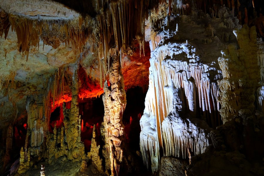 A cave interior with various stalactites and stalagmites, illuminated by red, blue, and white lights creating a contrasting effect. This lesser-known gem in Turkey is perfect for your next Travel Instagram post.