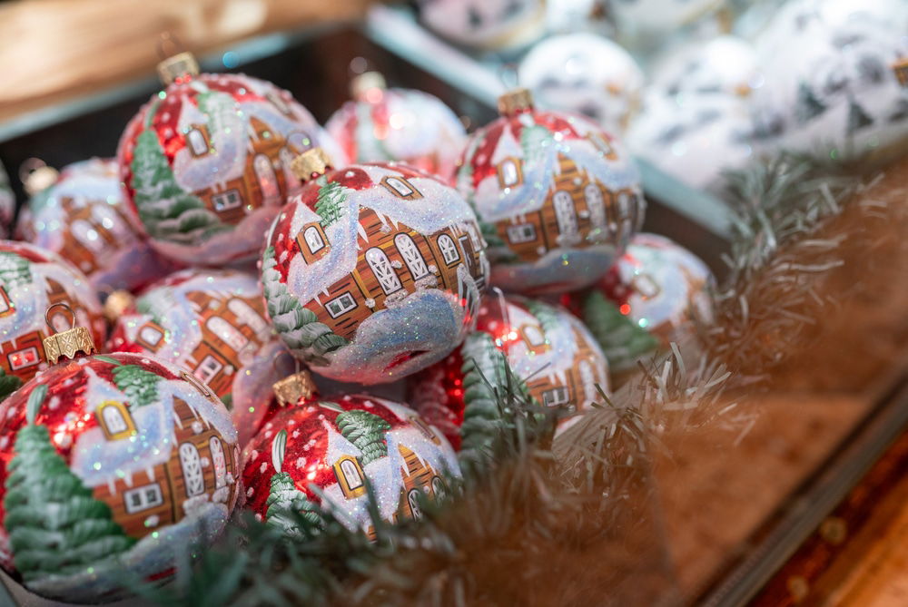 A collection of magical Christmas ornaments, decorated with houses and trees reminiscent of the best places to visit in Austria, displayed in a container.