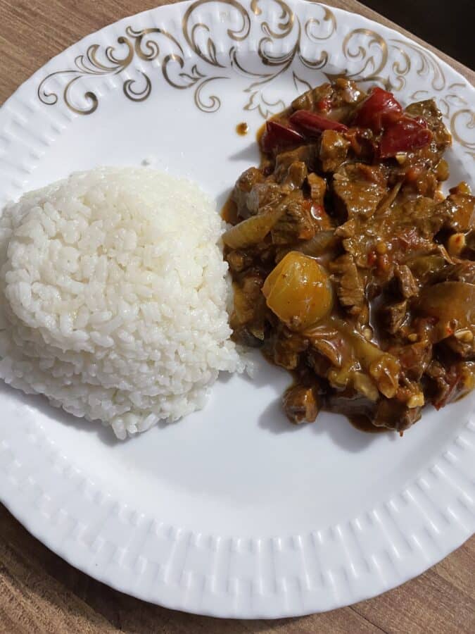 A plate of rice served with a beef and vegetable stir-fry on a decorative plate.