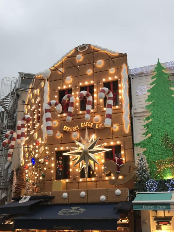 A building in Istanbul is whimsically designed like a gingerbread house, adorned with candy cane decorations and a large illuminated star on the facade, evoking the spirit of Christmas for all who pass by.