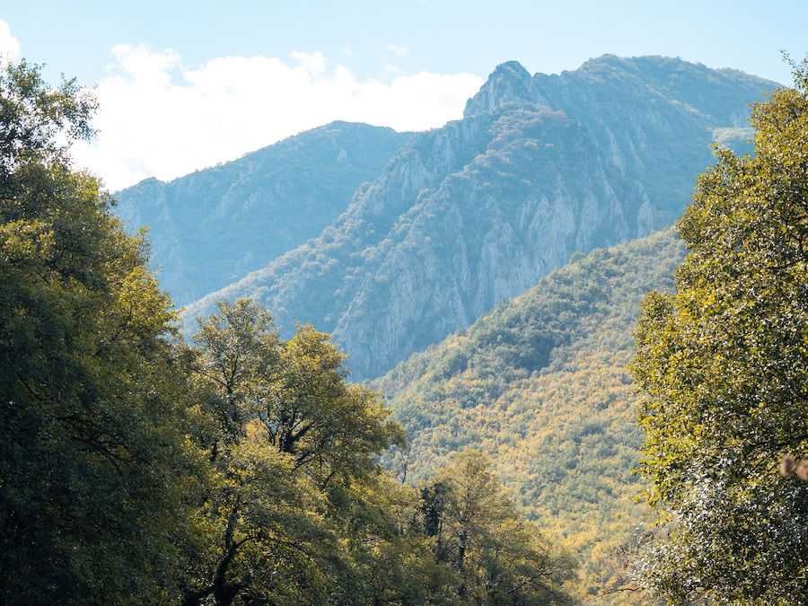 The mountain landscape, reminiscent of Skopje's Matka Canyon, boasts forested slopes and rugged peaks under a clear sky that inspires any nature guide.